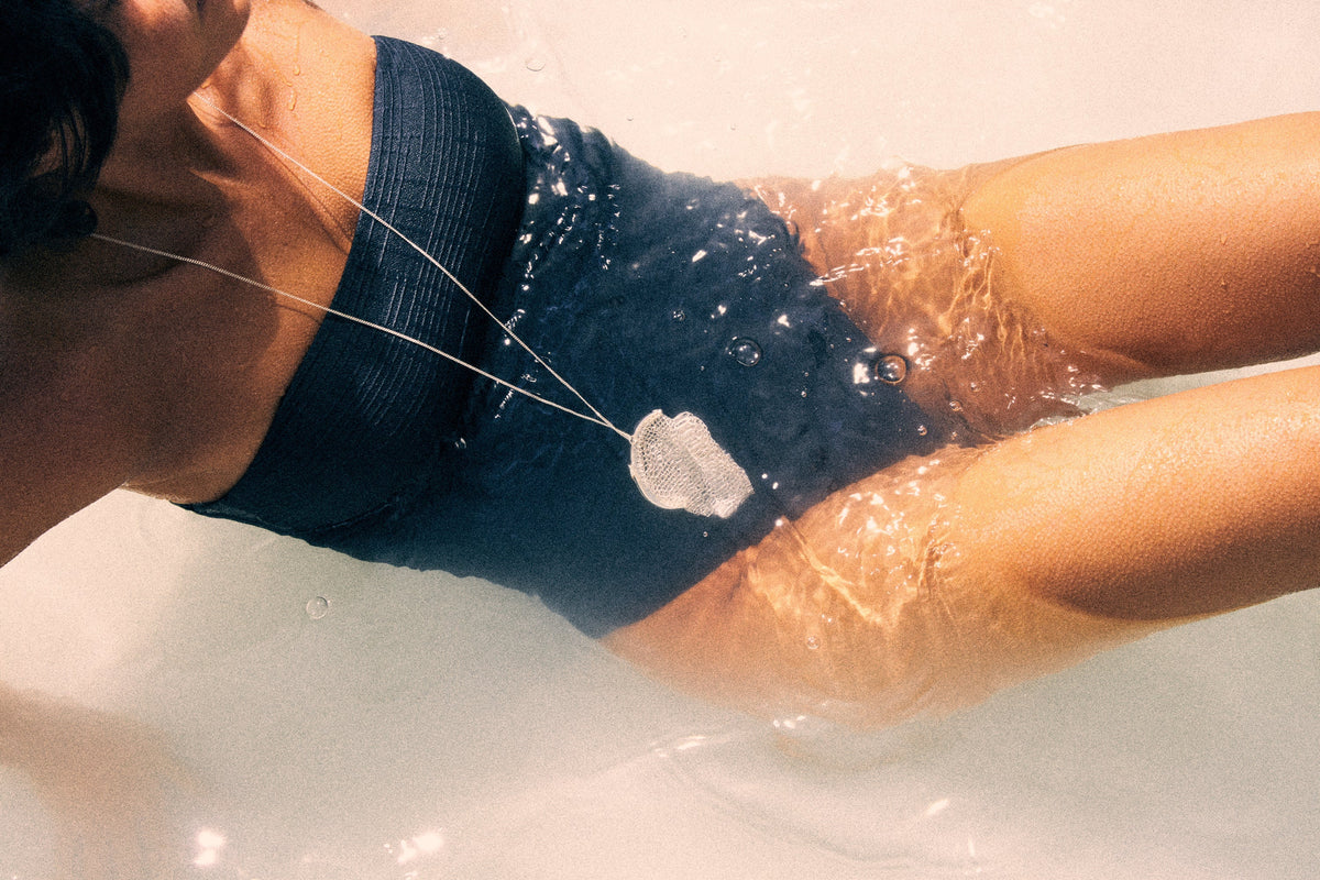 Woman wearing a boho mesh wallet necklace while relaxing in water, showcasing effortless summer style.