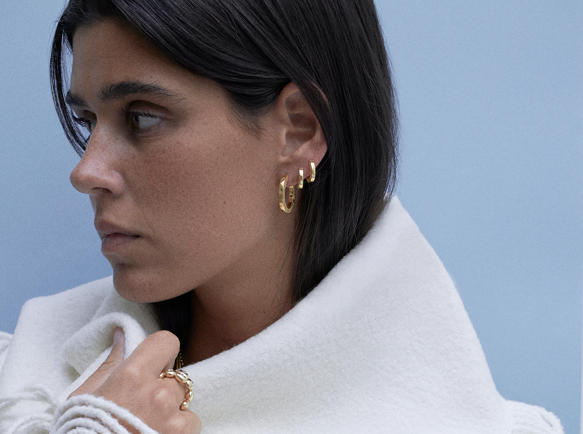 Close-up of a woman wearing gold hoops, showcasing timeless earring styles from CINCO Jewelry.