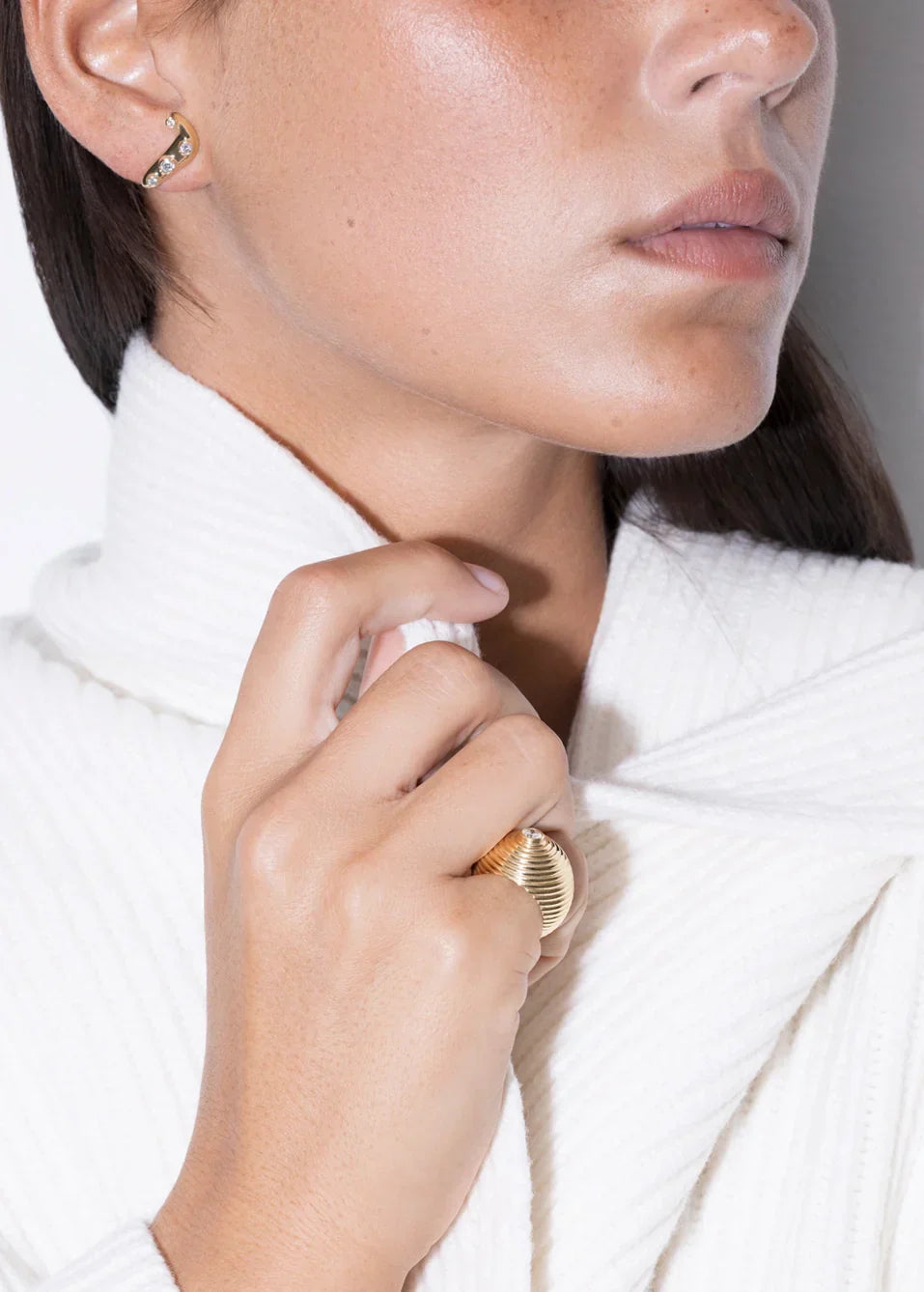 Close-up of a woman wearing elegant jewelry and a modern solitaire ring.