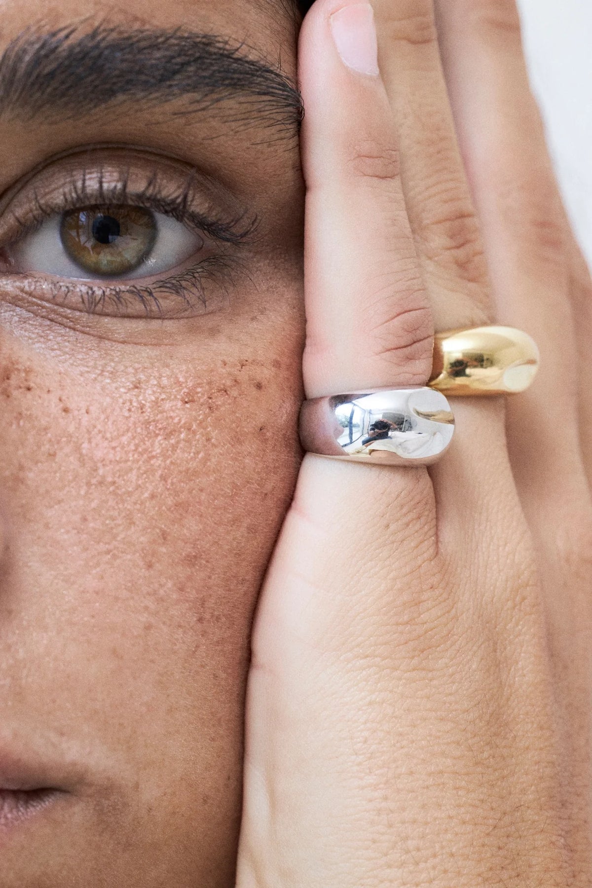Black Friday minimalist jewelry deals featuring gold and silver rings on a model's hand.
