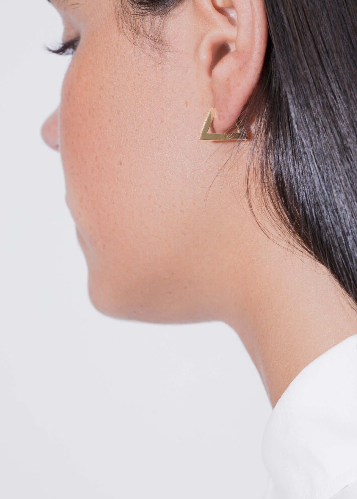 topaz triangle hoop earring worn on a woman's ear showcasing its unique triangle design and elegant gold finish.