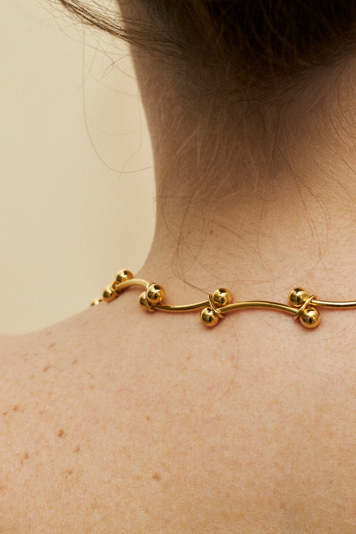 handcrafted silver and gold necklaces with spherical accents worn around the neck.