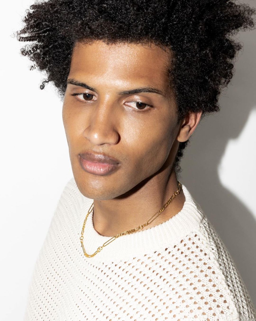 Person wearing a gold necklace from the gender neutral jewelry collection, showcasing modern and versatile design.