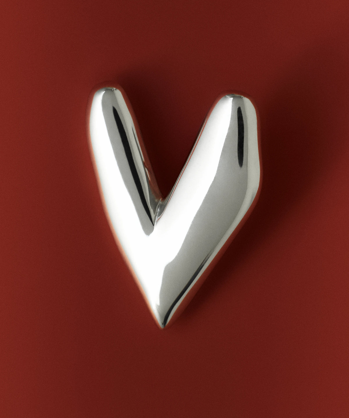 Heart-shaped jewelry gifts, featuring a polished silver heart pendant against a red background.