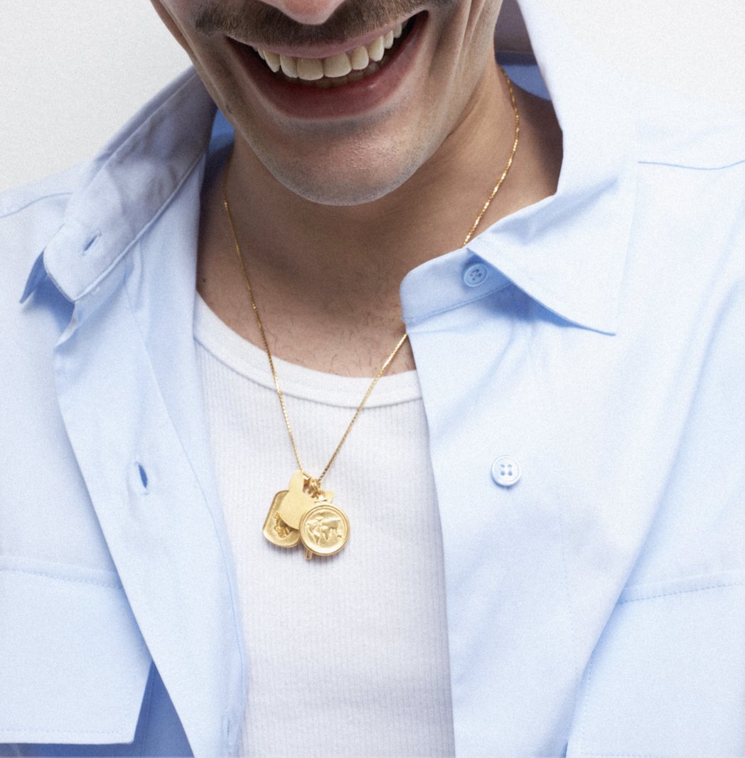 Handmade coin necklaces featuring two gold coin pendants worn on a chain by a smiling man.