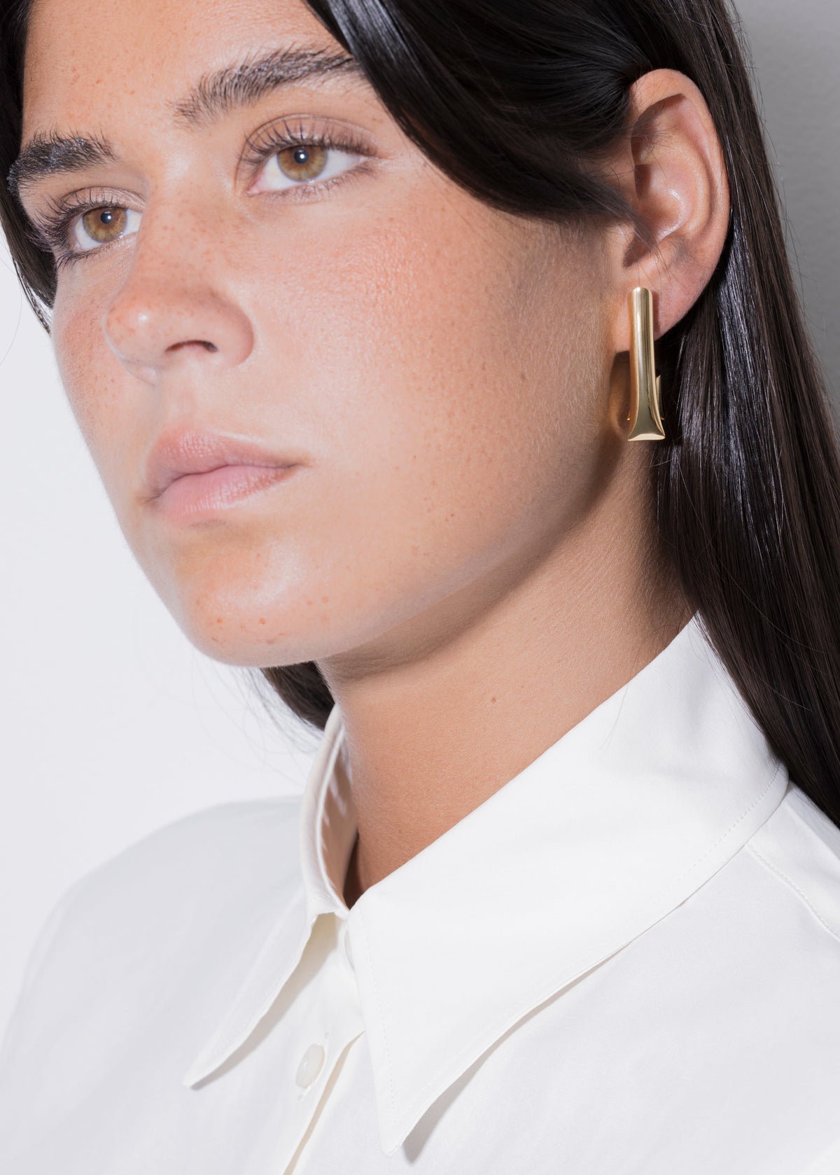 Close-up of a model wearing Tina family sterling silver earrings in a stylish setting.