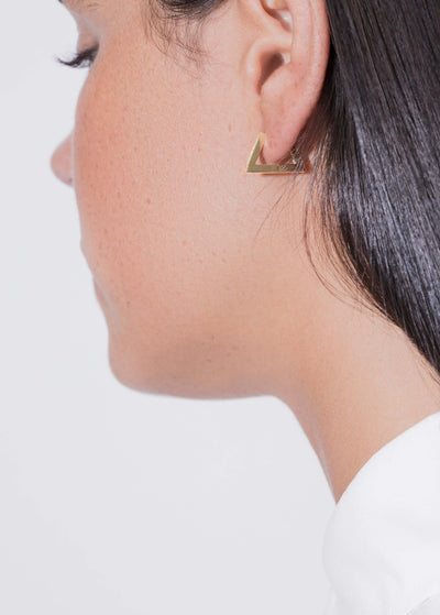 topaz triangle hoop earring worn on a woman's ear showcasing its unique triangle design and elegant gold finish.