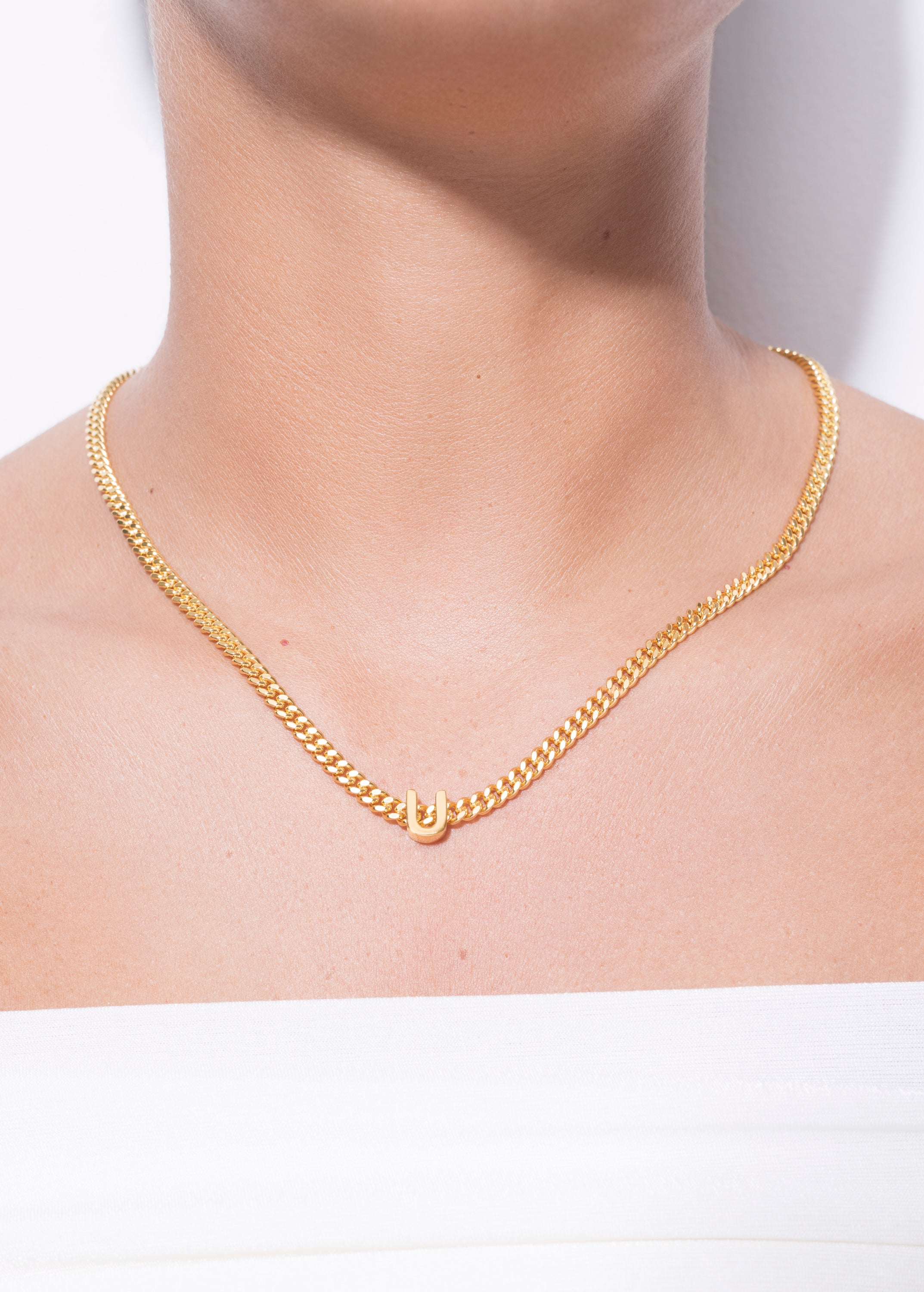 model wearing alphabet necklace with pendant U in gold