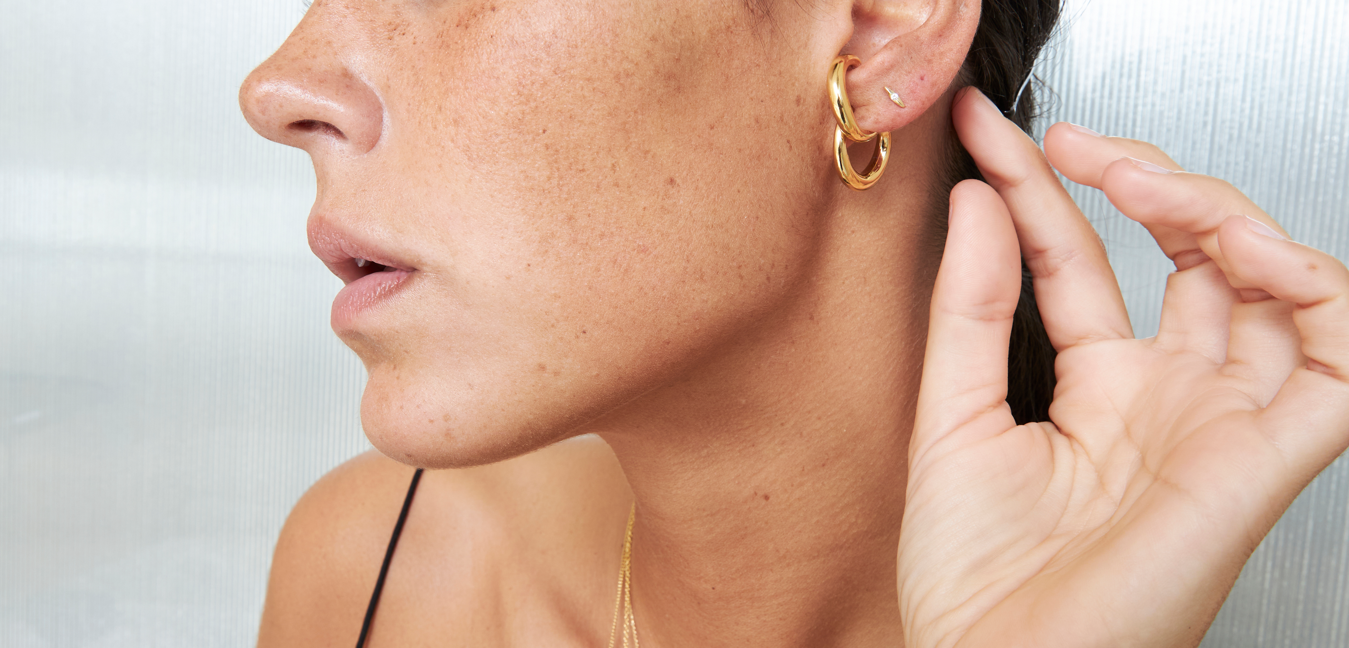 Close-up of woman adjusting an earring in front of a mirror