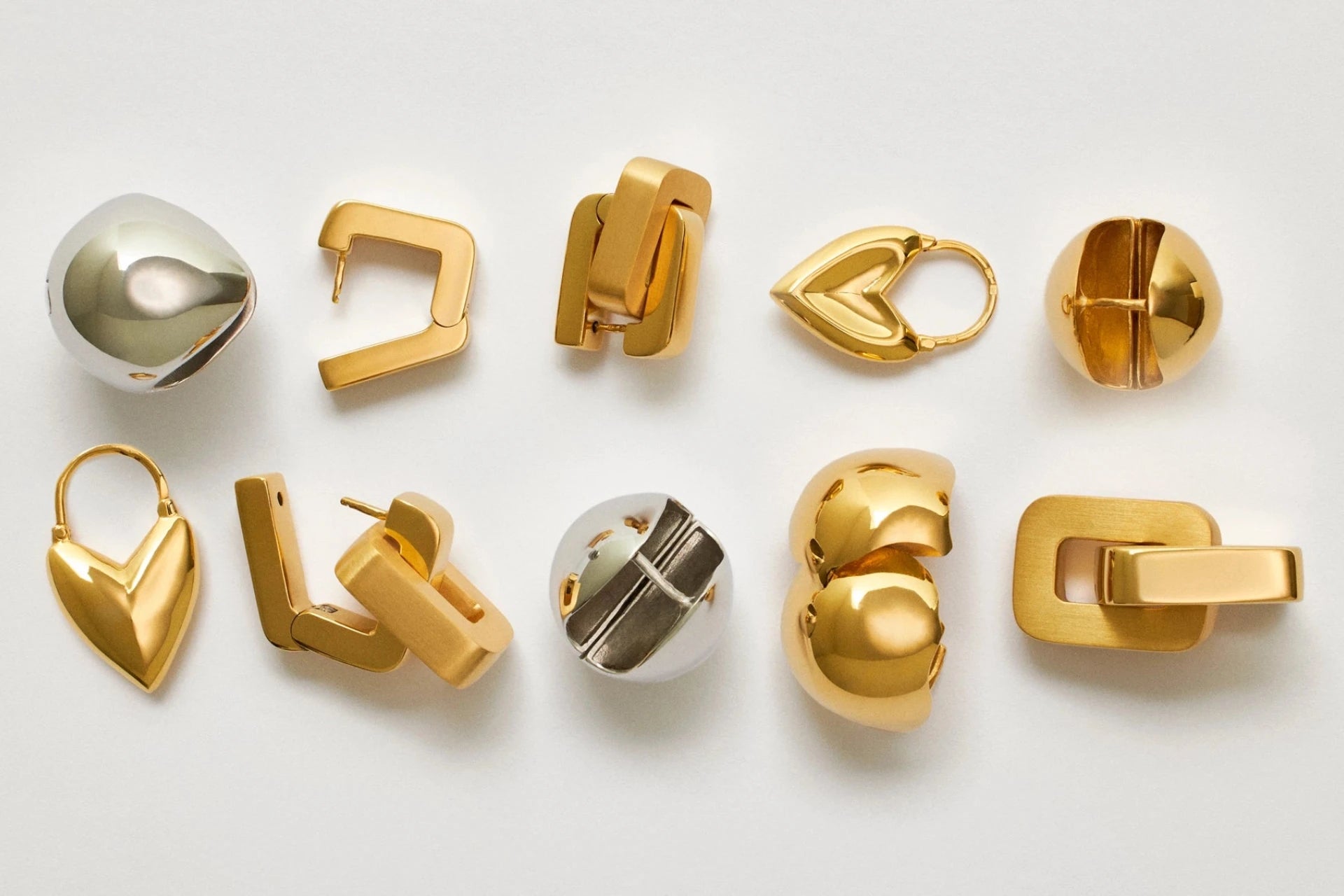 Collection of gold earrings on a light gray background