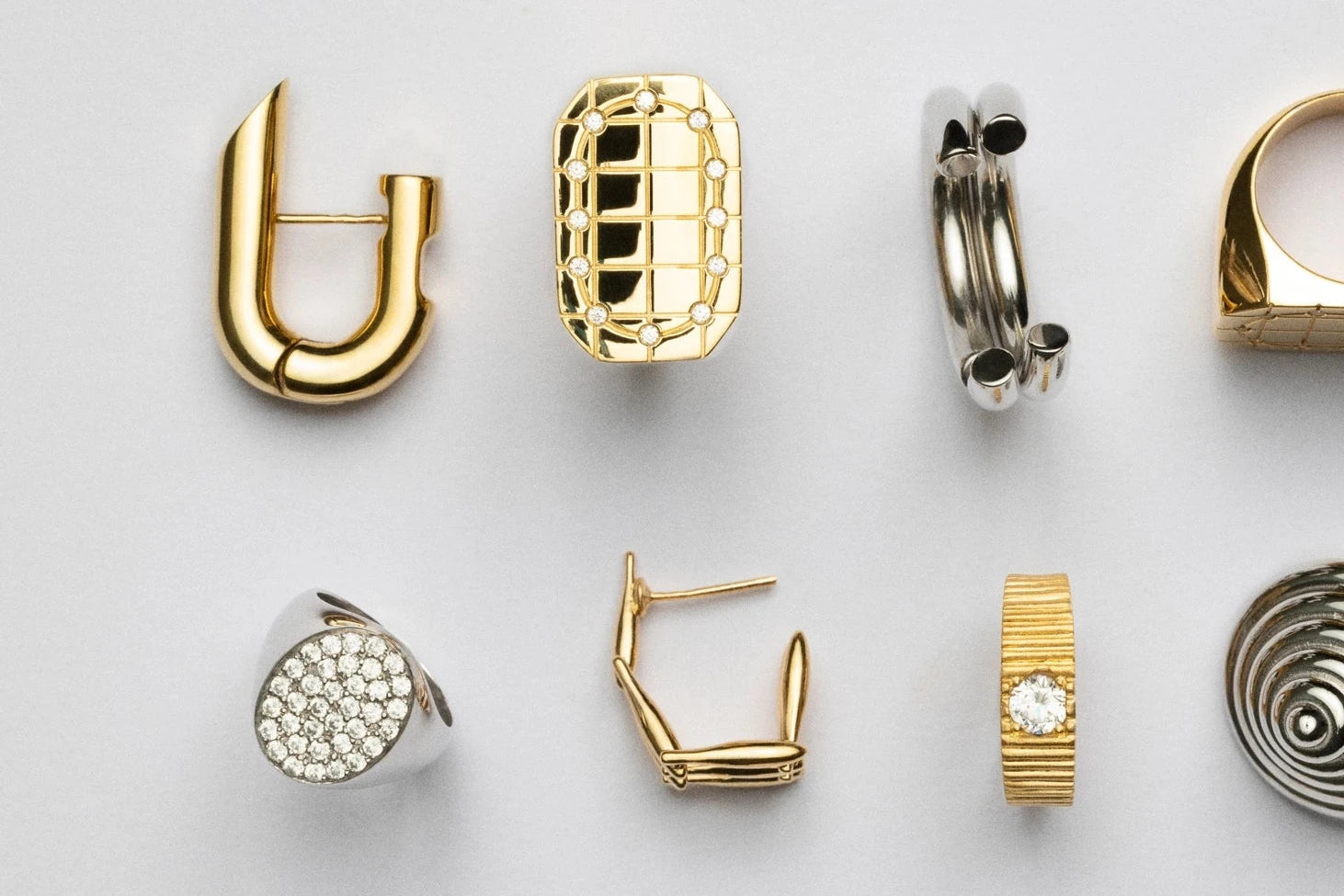 Collection of various gold and silver earrings on a light gray background