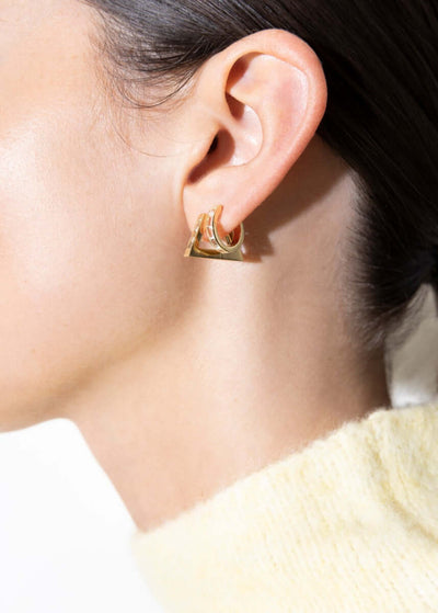 Topaz triangle hoop earring showcased on model's ear, highlighting its distinctive design and 18k gold craftsmanship.