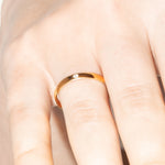 Gold ring on a person's finger against a neutral background